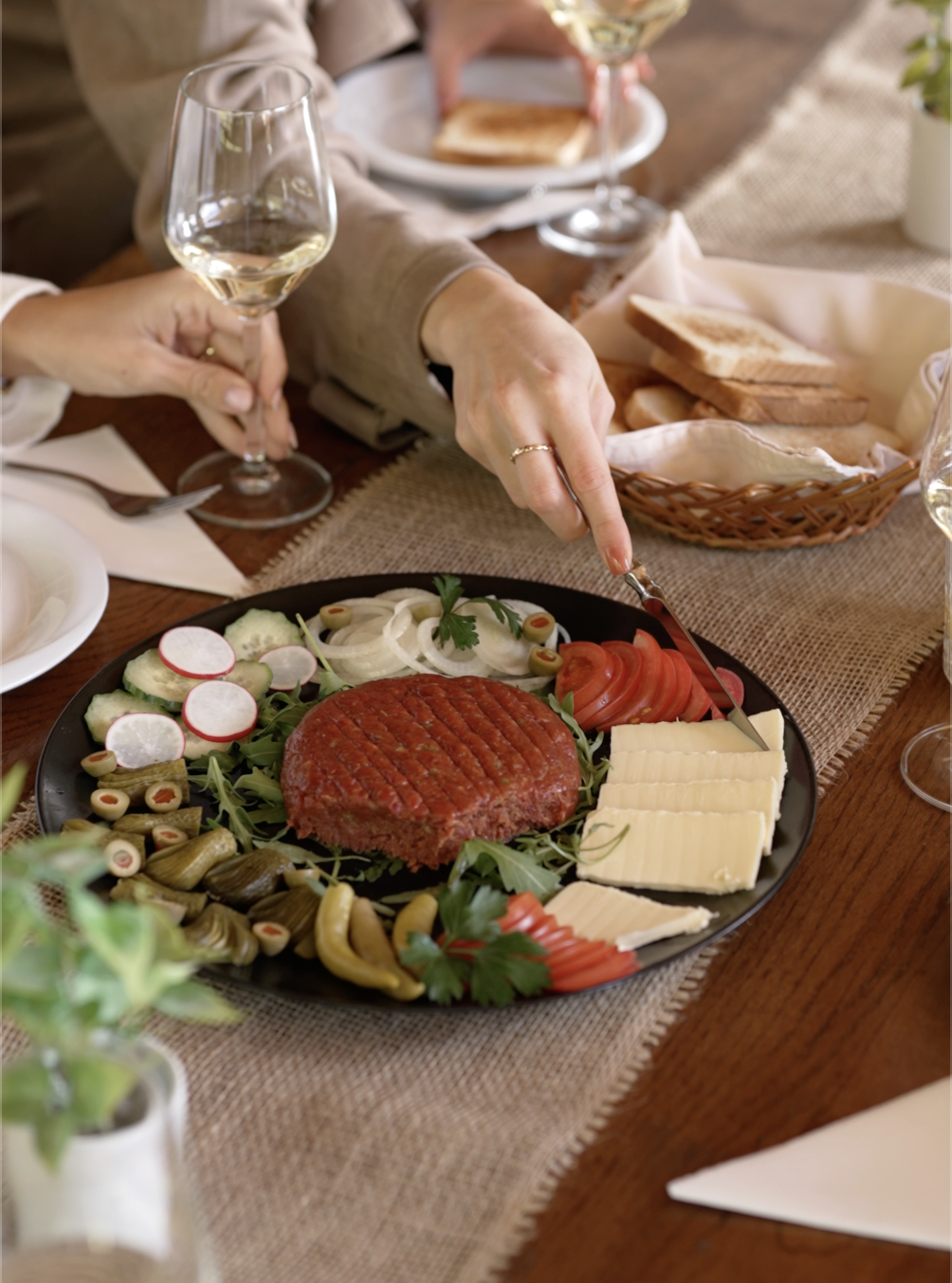 Predjed z domačo tartare, zelenjavo in sirom na črnem krožniku