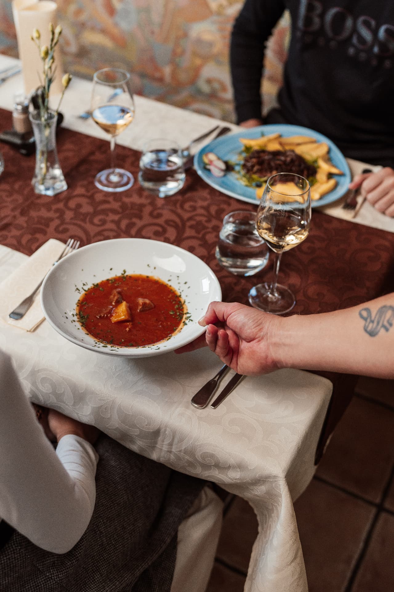 Postrežena domača juha ob kozarcu vina v Gostišču Sobočan